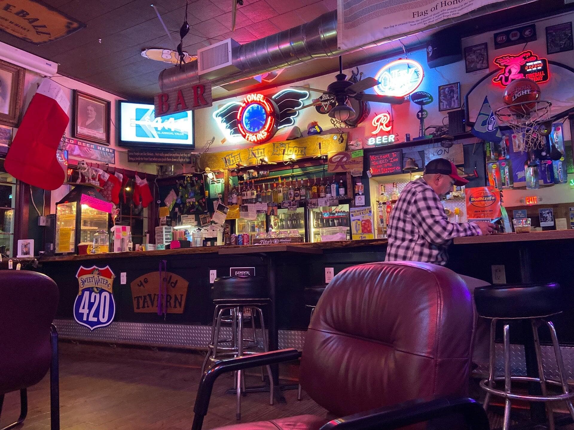 The tavern's split-log bar at night, its back wall crowded with glowing neon beer signs